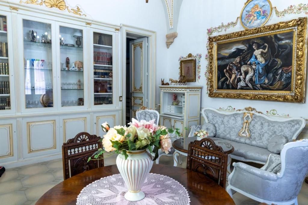 Une pièce comprenant une table à manger, des chaises, un canapé, un meuble avec des portes en verre et un tableau encadré accroché au mur.