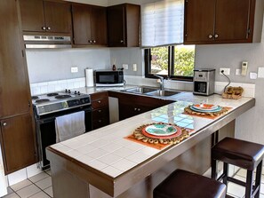 A kitchen with a central island, a stove, a microwave, a toaster, and a sink. - Walk to Beach - Pool Access - Walk to Restaurants - Laguna Vista (San José del Cabo)