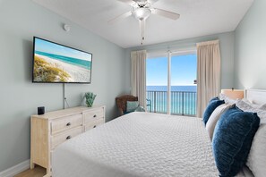 Ein Schlafzimmer mit einem großen Bett, einem Flachbildfernseher, einem Deckenventilator und Blick aufs Meer.