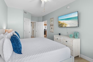 A bedroom with a bed, a dresser, a television, and a door leading to a bathroom. - *Majestic Sun A701*Updated*Heated Pools +Hot Tubs*Gym*Pickleball & Tennis* (Miramar Beach)