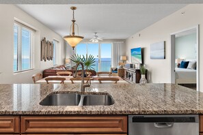 A modern kitchen with granite countertops, stainless steel appliances, and a dining area with a view of the ocean. - *Majestic Sun A701*Updated*Heated Pools +Hot Tubs*Gym*Pickleball & Tennis* (Miramar Beach)