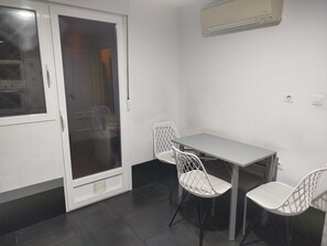 Ein Zimmer mit einer Schiebetür aus Glas, einem weißen Tisch mit vier Stühlen und einer an der Wand montierten Klimaanlage.