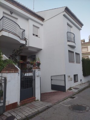 A two-story building with a white facade, a black gate, and a small balcony with a metal railing. - Single-family home in "Cenes De la Vega," ideal for families (Cenes de la Vega)
