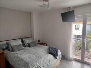 A bedroom with a bed, a bedside table, a TV mounted on the wall, and a balcony with a view. - Single-Family Home in "Cenes De la Vega," Ideal for Families (Cenes de la Vega)