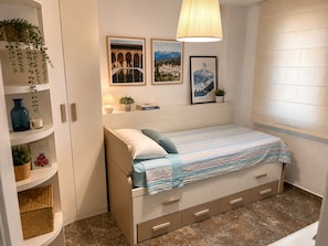 A bedroom with a bed, a shelf with plants, a lamp, and framed pictures on the wall. - Single-Family Home in "Cenes De la Vega," Ideal for Families (Cenes de la Vega)