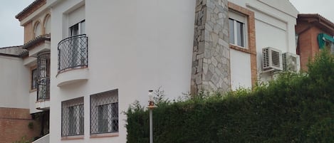 Un edificio de dos plantas con una chimenea de piedra, varios balcones y un acceso con portón.