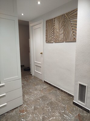 A hallway with a white door, a wardrobe, and a textured wall with decorative panels. - Single-family home in "Cenes De la Vega," ideal for families (Cenes de la Vega)