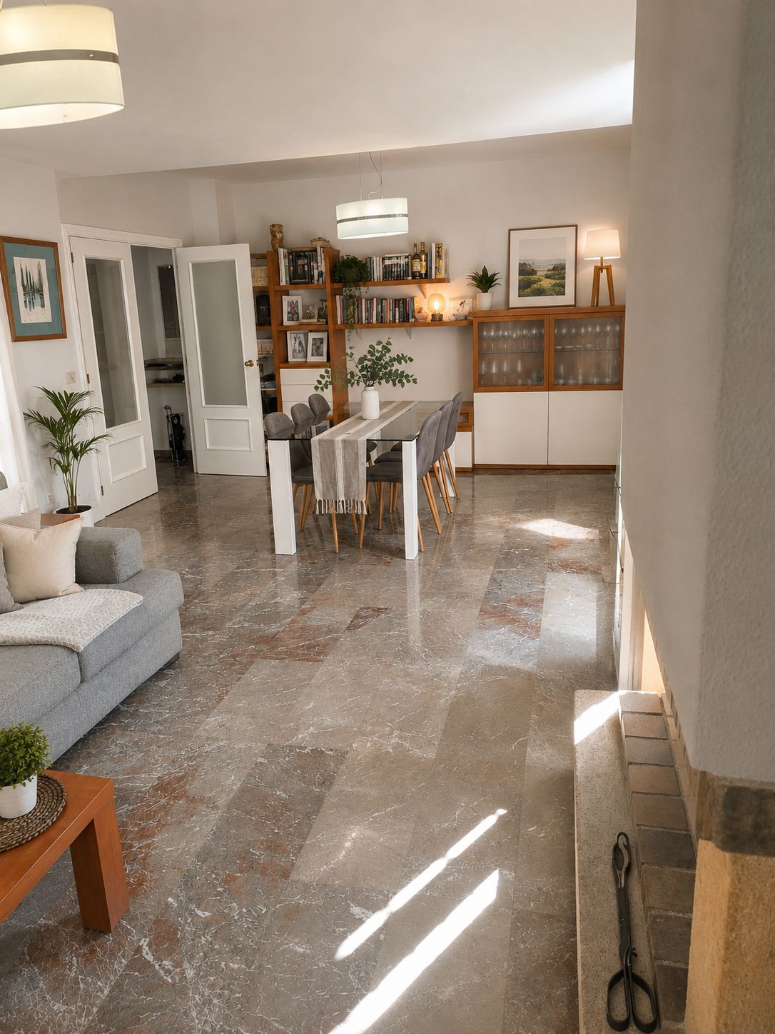 A spacious living area with a dining table, seating, a sofa, a bookshelf, and a kitchen area with cabinets and a countertop.