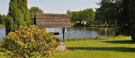 A bench by a lake with a grassy foreground and trees in the background.
