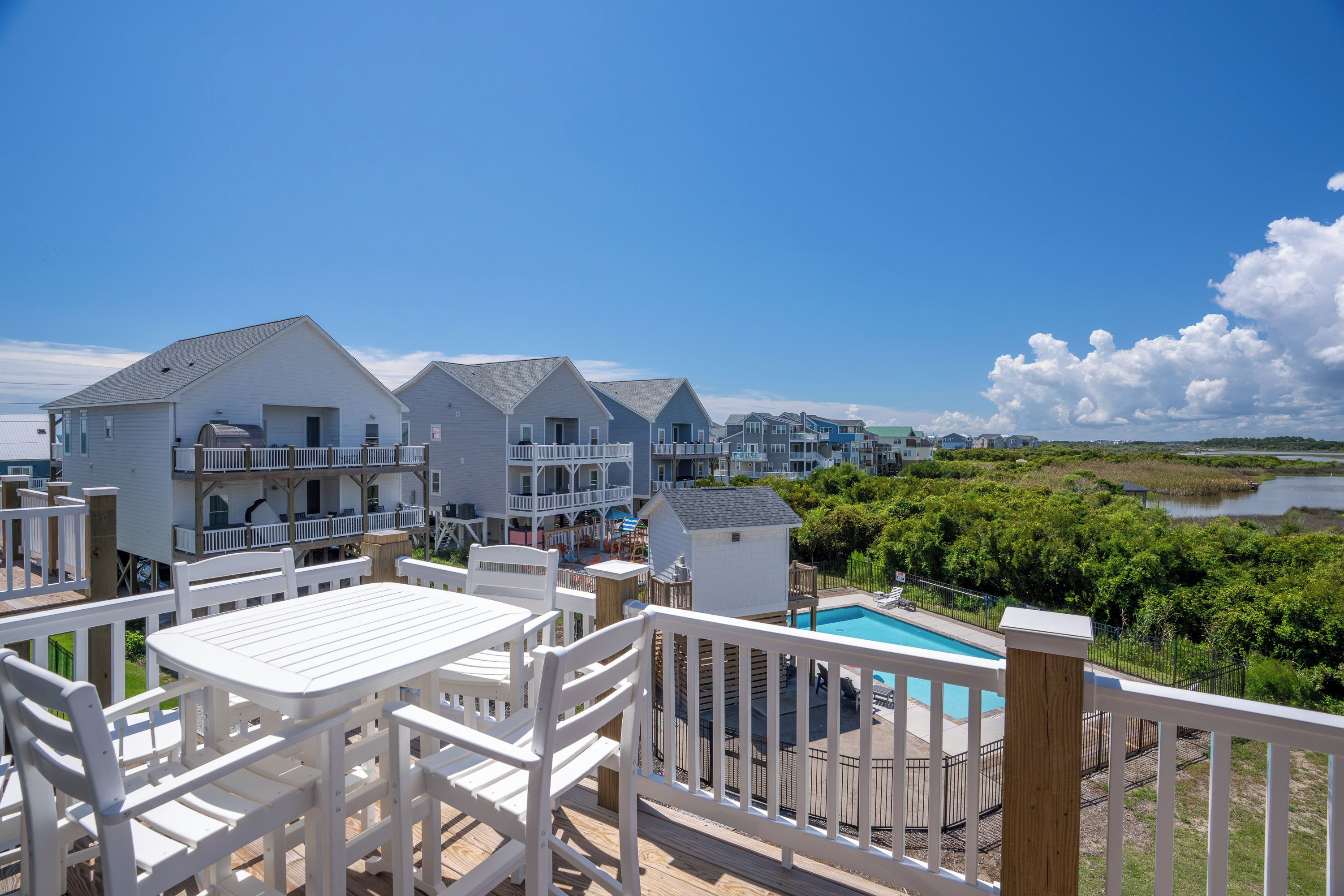 A residential area with multiple houses, a swimming pool, and a view of a body of water.