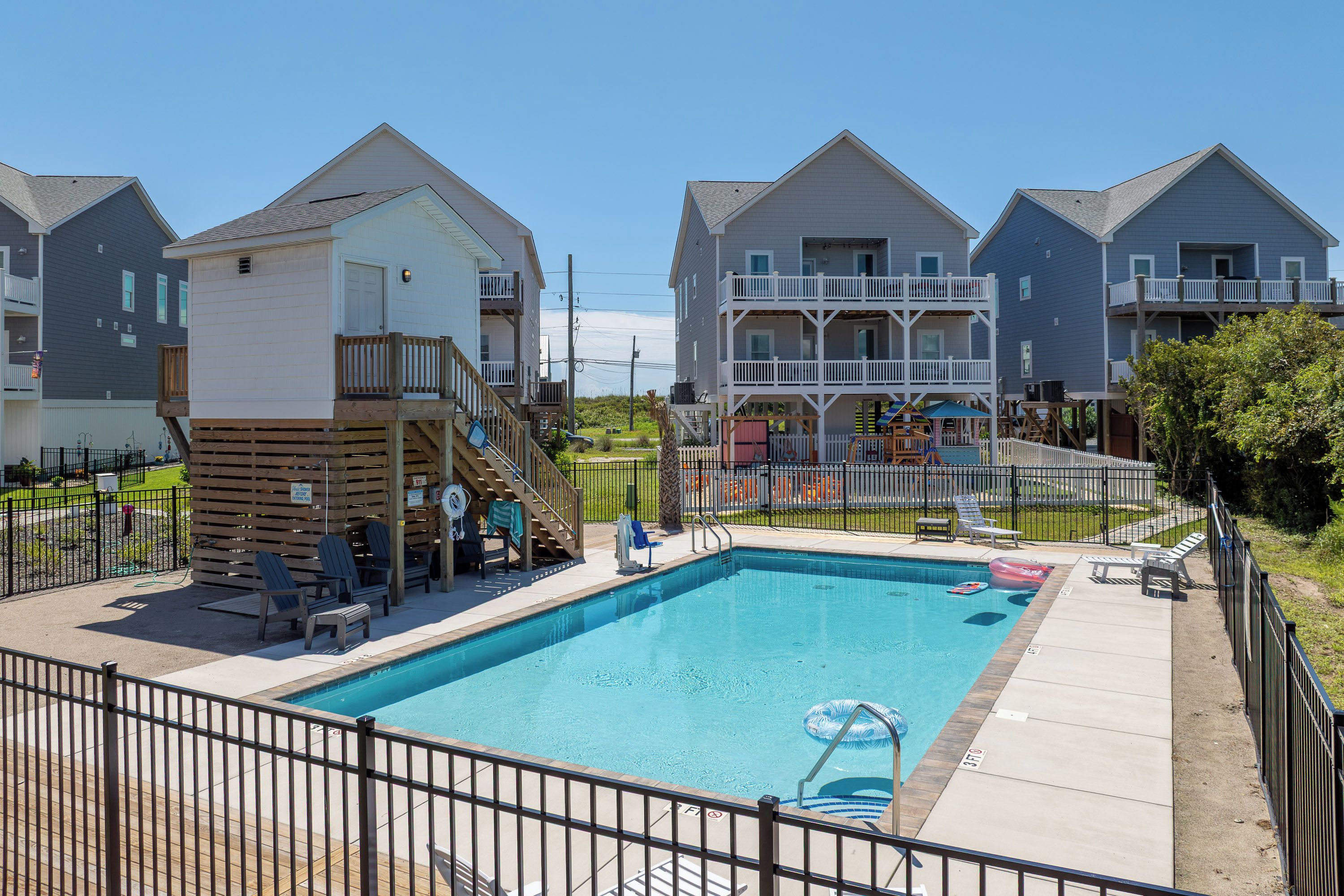 A swimming pool with a wooden deck, lounge chairs, and a lifeguard stand.