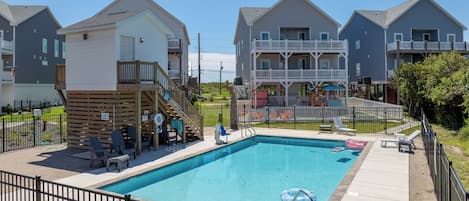 A swimming pool with a wooden deck, lounge chairs, and a lifeguard stand.