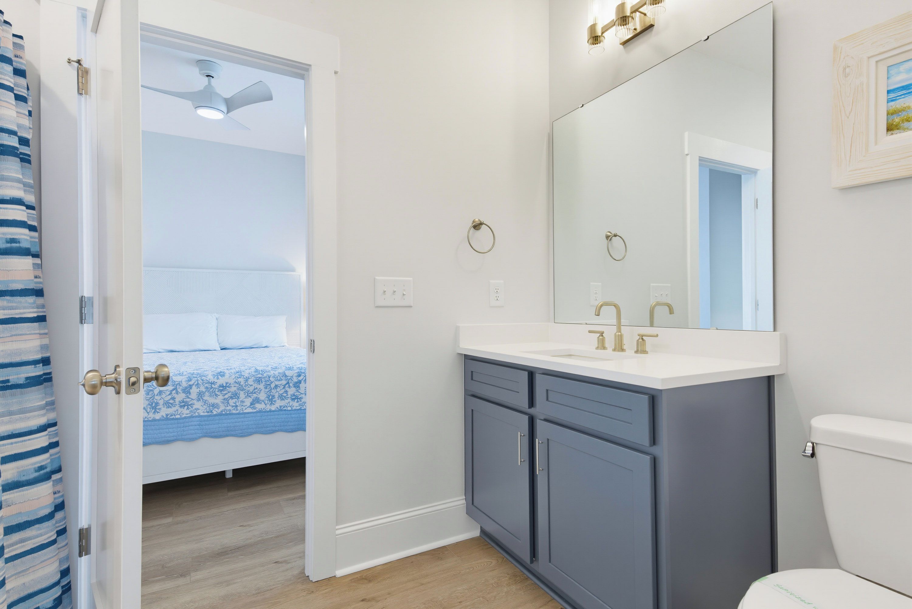 A bathroom with a white toilet, a double sink vanity, and a large mirror.