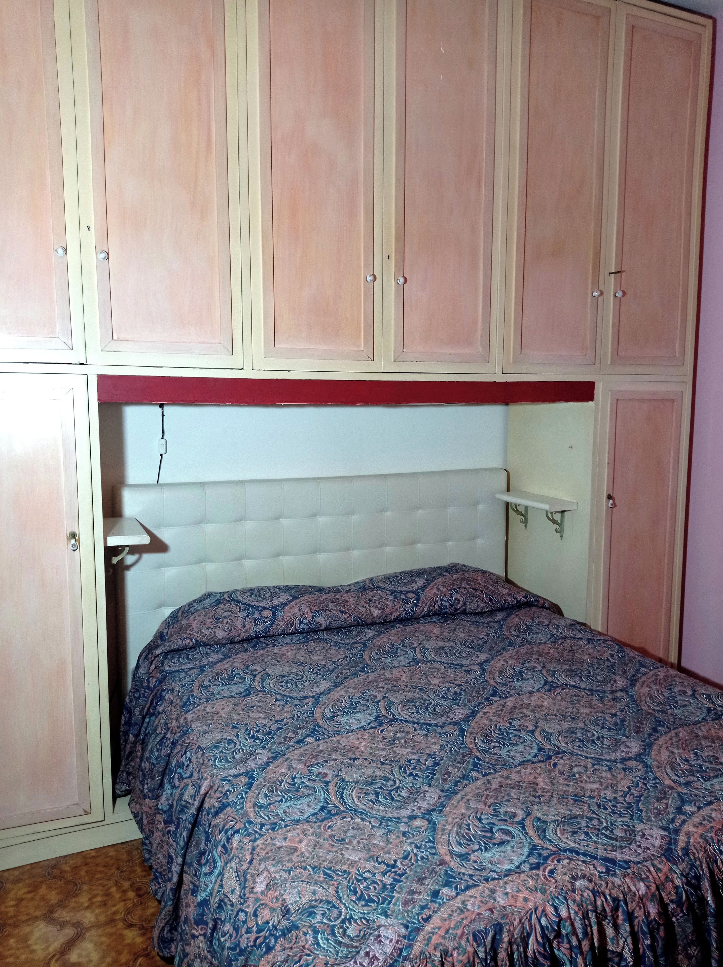 A bedroom with a bed, a headboard, and a wardrobe.