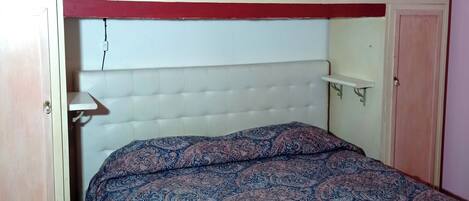 A bedroom with a bed, a headboard, and a wardrobe.