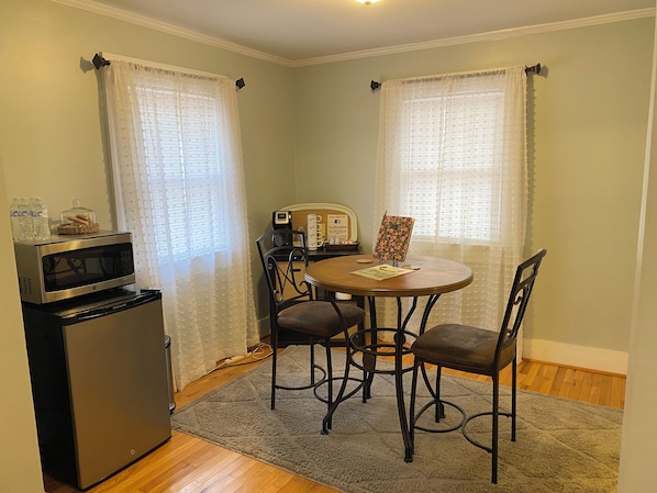 A compact kitchen with a refrigerator, microwave, and a small dining table with chairs.