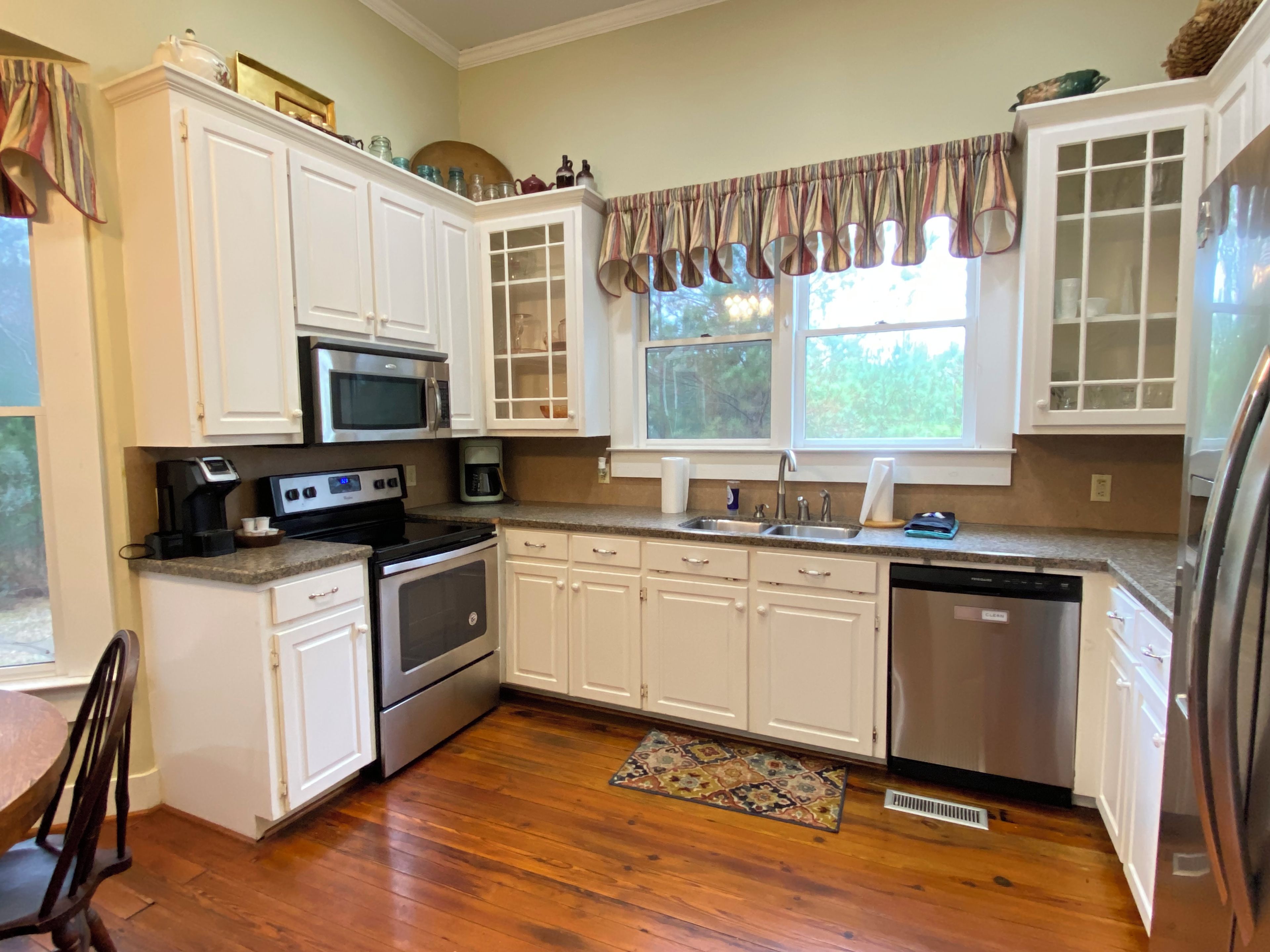 A kitchen with white cabinets, stainless steel appliances, a microwave, a coffee maker, and a dishwasher.