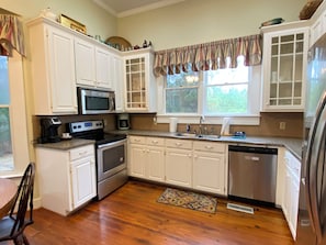 A kitchen with white cabinets, stainless steel appliances, a microwave, a coffee maker, and a dishwasher.