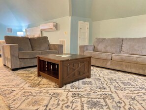 A living room with two sofas, a coffee table, and a patterned rug.