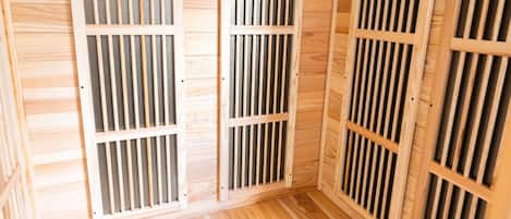 A sauna room with wooden slats and a ceiling vent.