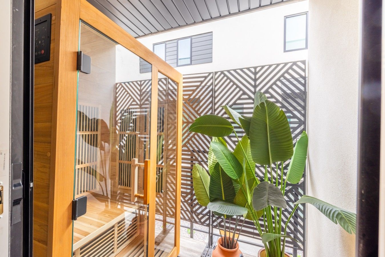 A modern room with a wooden sliding door, a glass partition, and a patterned wall.