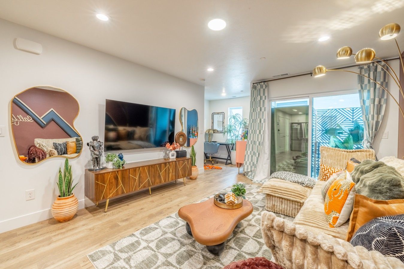 A modern living room with a flat-screen TV, a wooden console table, and a sofa with patterned cushions.
