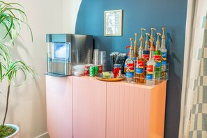 A hotel reception area with a coffee machine, a menu board, and a variety of toiletries including hand sanitizers and personal care products.