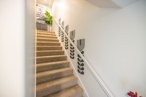 A carpeted staircase with a white wall featuring a leaf pattern.