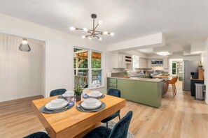 Een moderne keuken met een centraal eiland, houten vloeren en een eetgedeelte met een tafel gedekt voor vier personen.