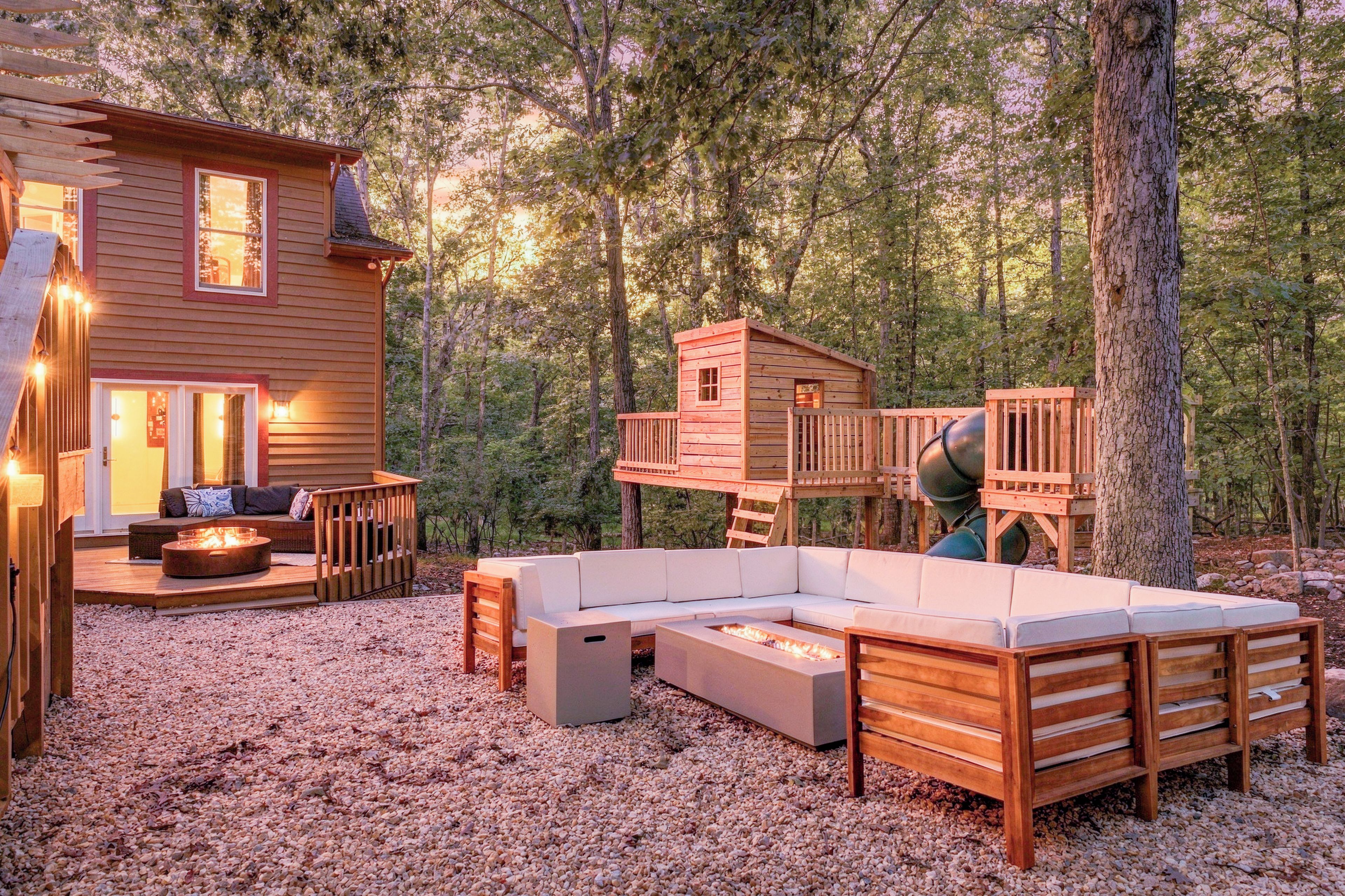 A cabin with a deck, outdoor seating, and a fire pit.