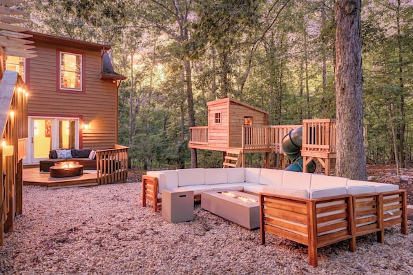 A cabin with a deck, outdoor seating, and a fire pit. - 7BR w Treehouse, Hot Tub, Sauna, Theater. Pets OK! (McGaheysville)