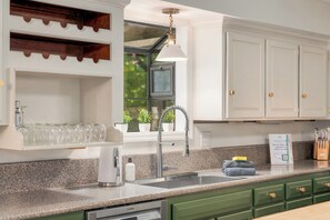 A kitchen with a built-in dishwasher, a stainless steel sink, and green cabinets. - 7BR w Treehouse, Hot Tub, Sauna, Theater. Pets OK! (McGaheysville)