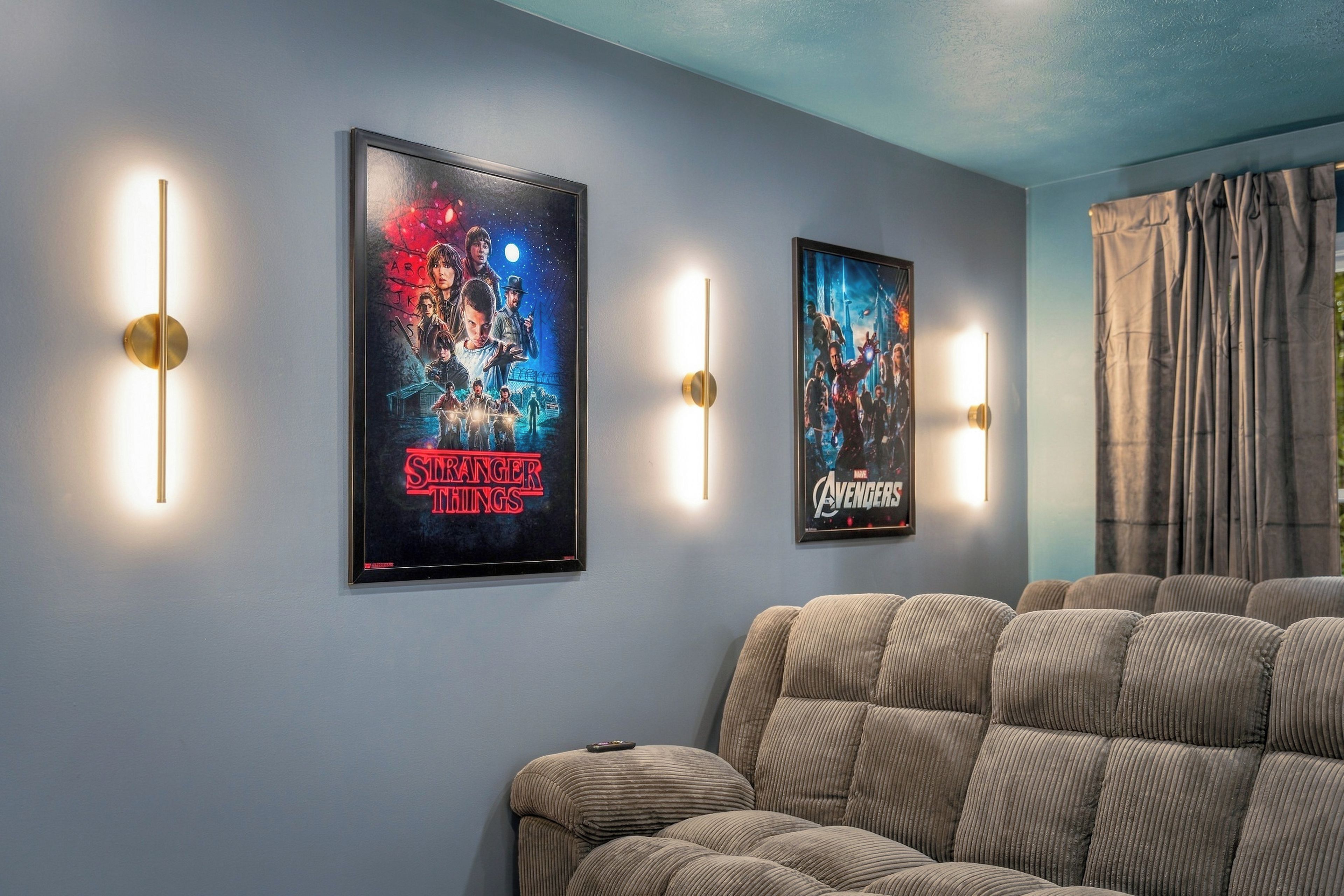 A room with two framed posters on the wall, a couch, and a window with curtains.
