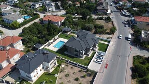 A residential area with multiple houses, a swimming pool, and a road.