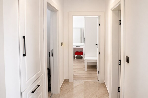 A hallway with white doors, a red bench, and a mirror on the wall.