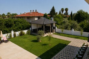 A residential property with a covered patio, a lawn, and a paved walkway.