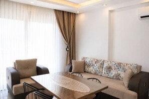 A modern living room with a sofa, two armchairs, a coffee table, and a dining table. - SESU 2 - Çamyuva'da Denize Yakın 2+1 Apart (Kemer)