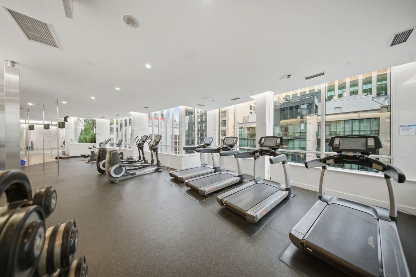 A modern gym with treadmills, elliptical machines, and free weights.