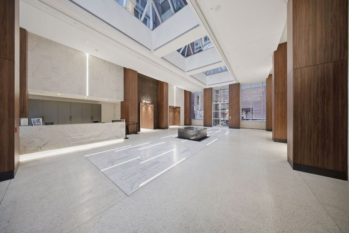 A spacious lobby with a reception desk, a seating area, and a high ceiling with skylights.