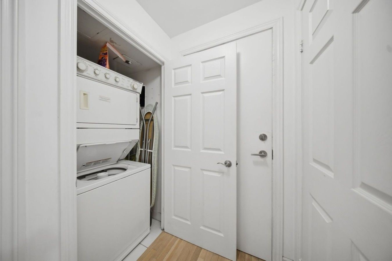 A laundry room with a washer and dryer, a door, and a small shelf with items.