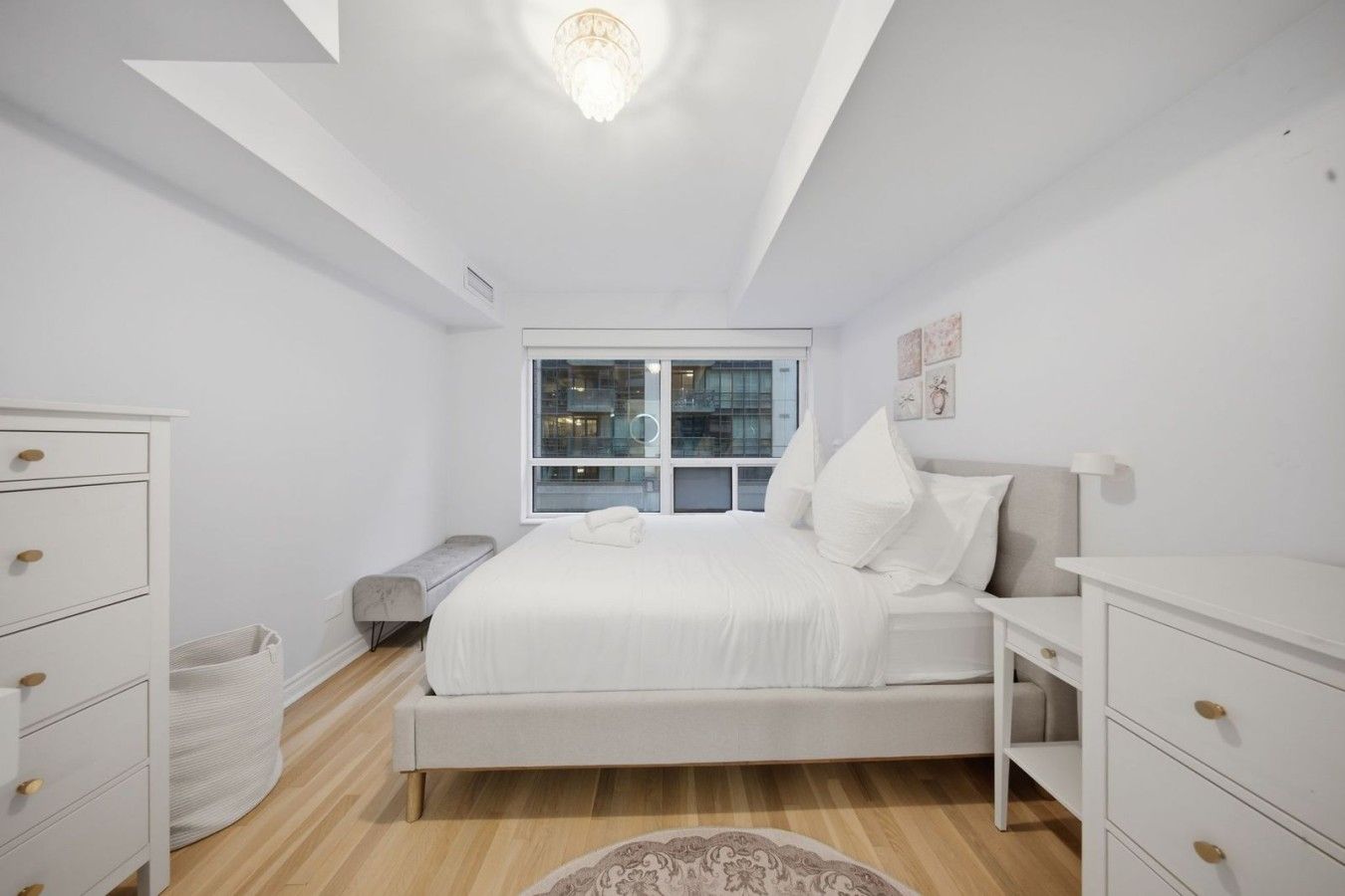 A minimalist bedroom with a bed, bedside tables, a bench, and a window.