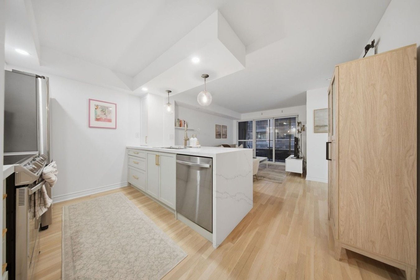 A modern kitchen with a central island, stainless steel appliances, and a wooden cabinet.