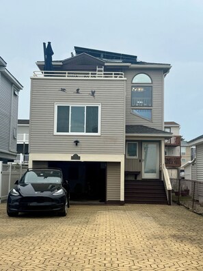 Een tweelaags huis met een garage, een auto ervoor en een trap die naar de bovenverdieping leidt.