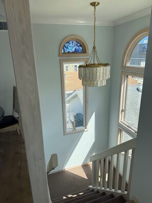 A staircase with a view of the outside, a hanging light fixture, and a window with a decorative frame.
