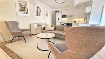 Een moderne woonkamer met een bank, twee fauteuils, een salontafel en kunst aan de muur.