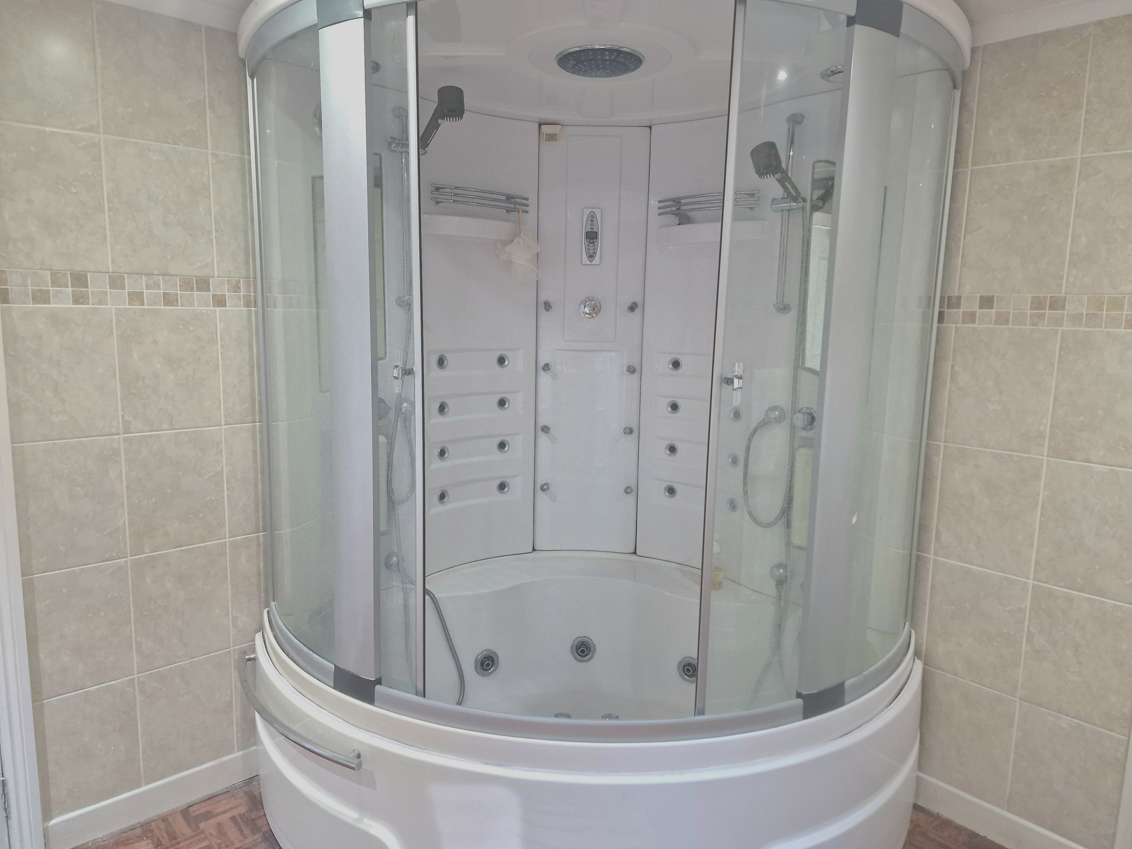 A modern bathroom with a glass-enclosed shower stall, a built-in toilet, and a vanity with a mirror.