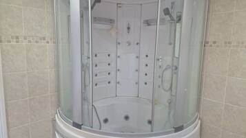 A modern bathroom with a glass-enclosed shower stall, a built-in toilet, and a vanity with a mirror.