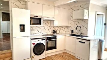 A compact kitchen with white cabinetry, a microwave, a sink, and a dishwasher.