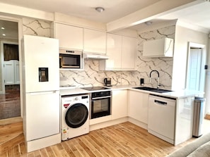 A compact kitchen with white cabinetry, a microwave, a sink, and a dishwasher.