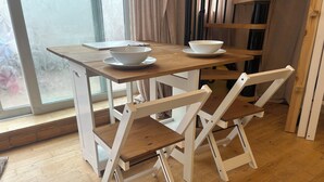A dining table with a bowl and saucer, two white chairs, and a window with curtains. - Independent, Modern Annexe in Orpington (Orpington)